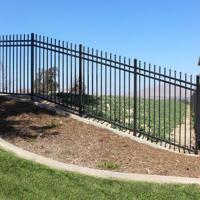 A durable black metal fence installed on a sloped landscape with a vineyard in the background.